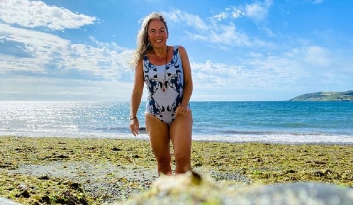 Woman walking from sea onto beach