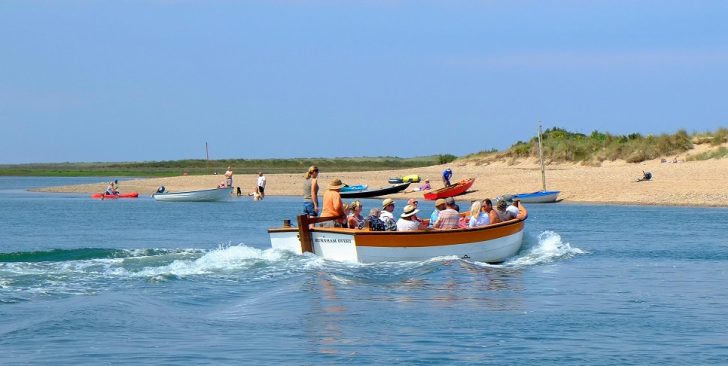 Boat full of people approaches beach on sunny day