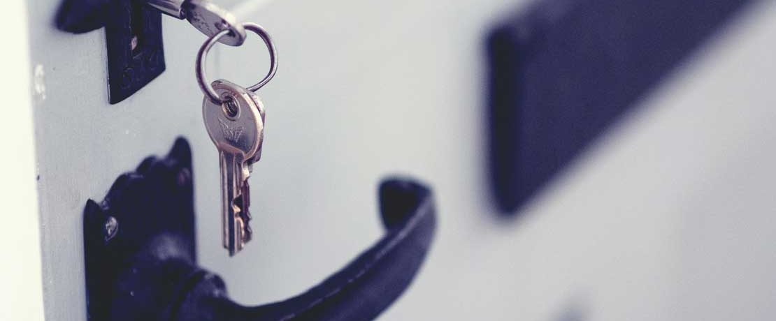 A silver key bunch hanging from the lock in a white painted door