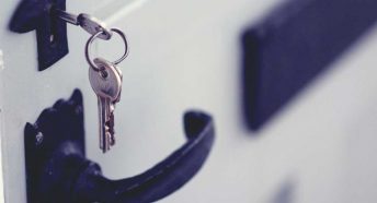 A silver key bunch hanging from the lock in a white painted door