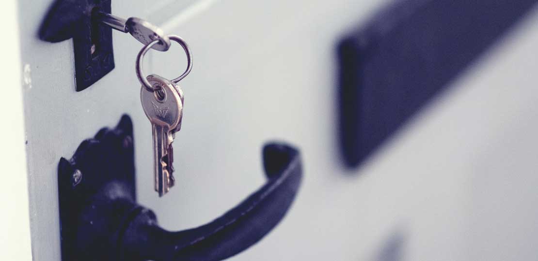 A silver key bunch hanging from the lock in a white painted door