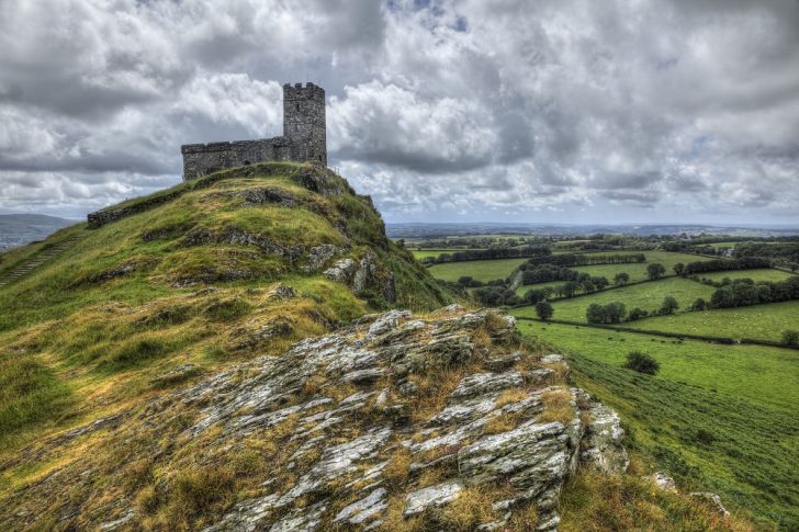 A small church at the end of a rocky ridge high up above a patchwork landscape of green fields and hedgerows