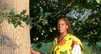 A woman standing beside a tree in parkland