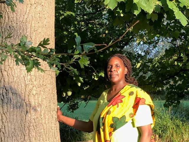 A woman standing beside a tree in parkland