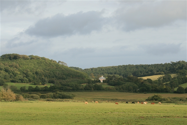 A distant house nestled in a valley within rolling countryside