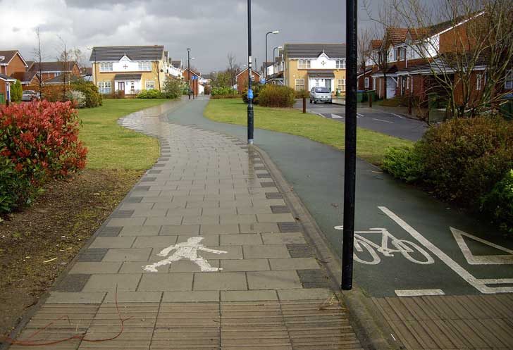 A walking pavement through a housing estate with a two-way cycle lane beside