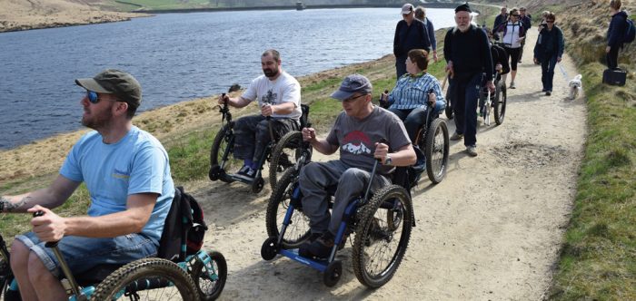 A group of wheelchair users enjoying a purpose-built route around a reservoir in an upland landscape