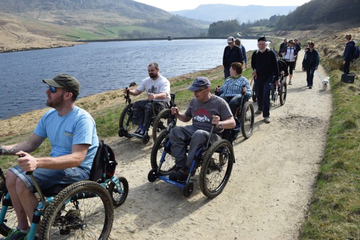 A group of wheelchair users enjoying a purpose-built route around a reservoir in an upland landscape
