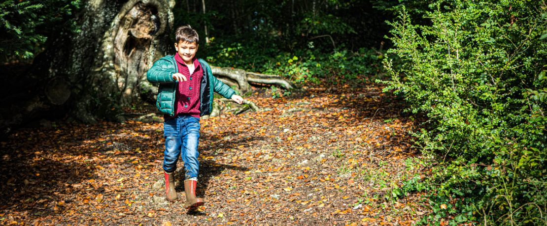 boy running down a footpath covered in leaves