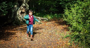 boy running down a footpath covered in leaves
