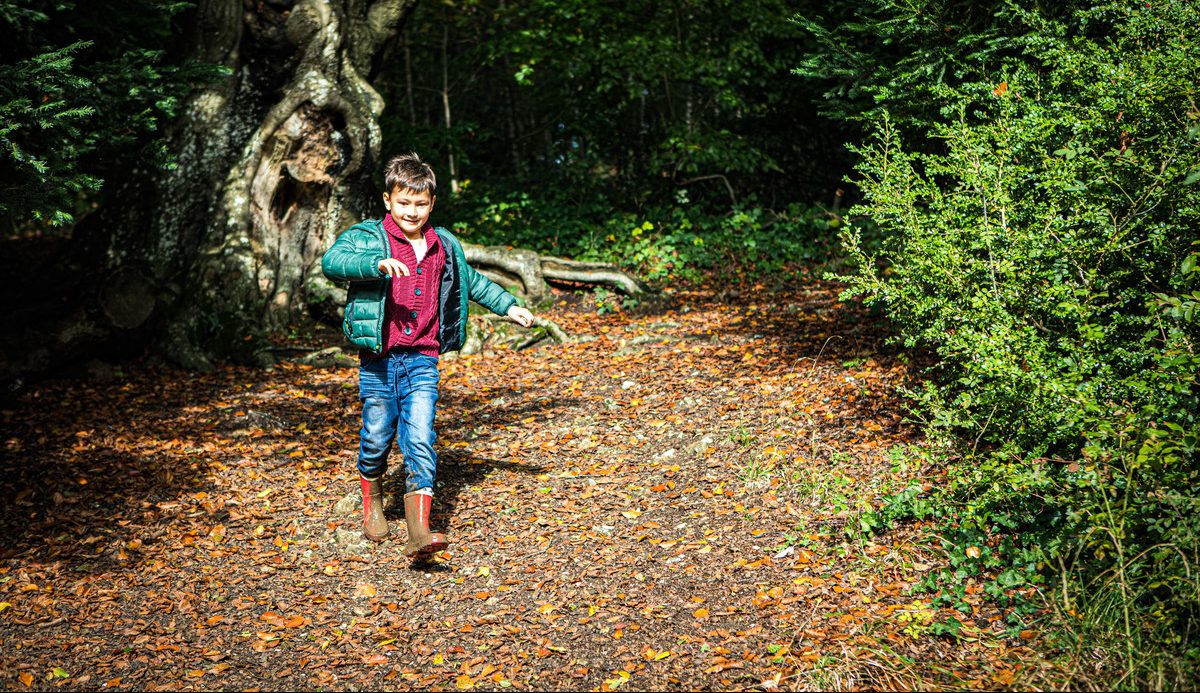 boy running down a footpath covered in leaves