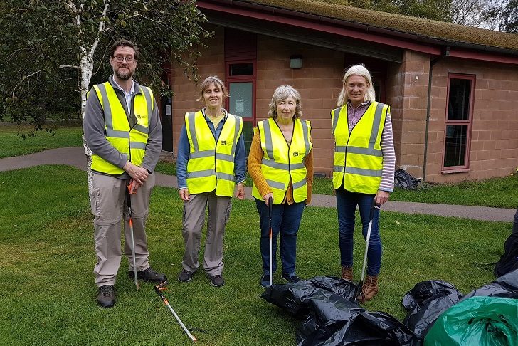 Four people in hi-vis vests and litter picking equipment and bin bags