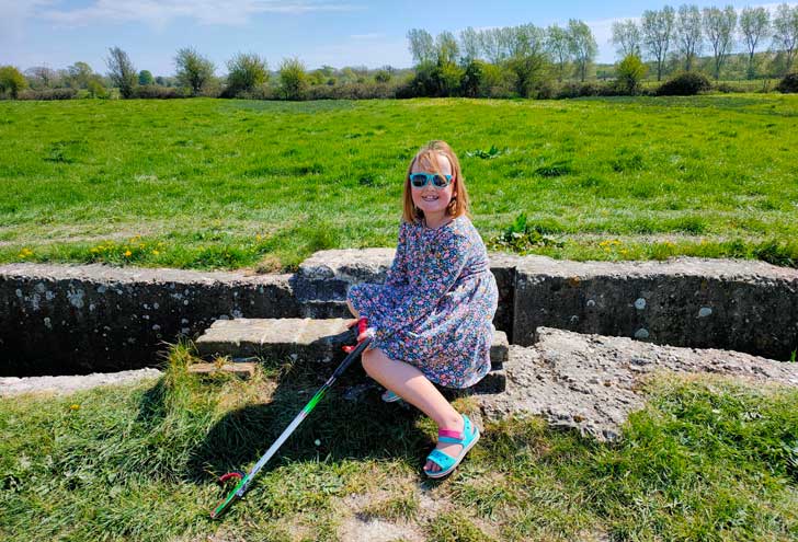 A young girl sitting down holding a litter picking device