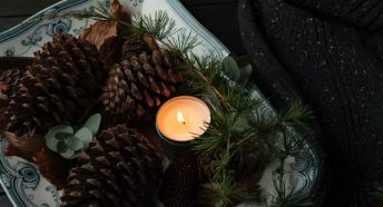 Pine cones and evergreens on a dish with a candle
