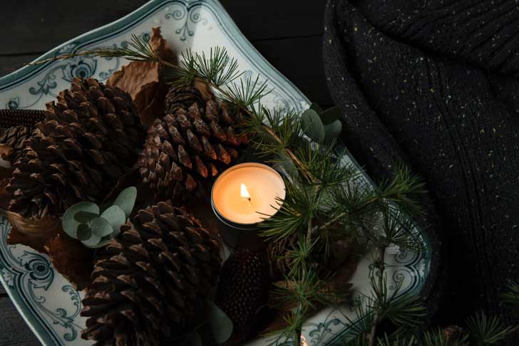 Pine cones and evergreens on a dish with a candle
