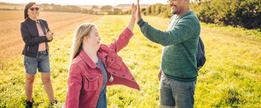 Family walking in a field with father and daughter doing a high five