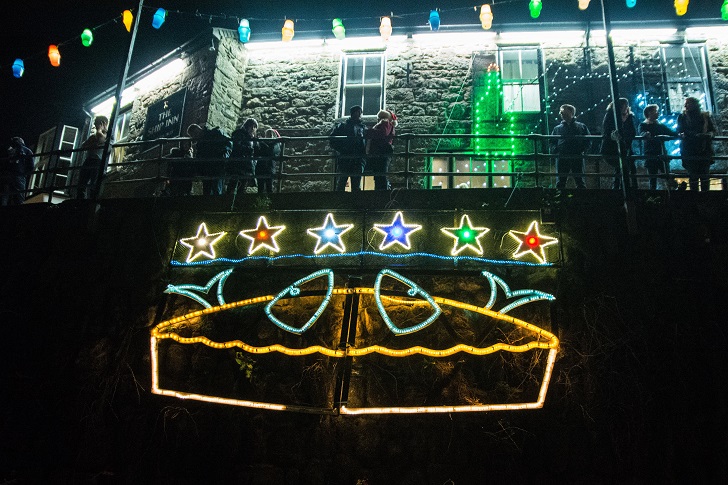 a pie made of lights on a harbour wall in front of a pub
