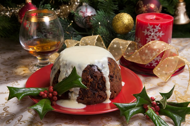 a Christmas pudding with white sauce and sprigs of holly