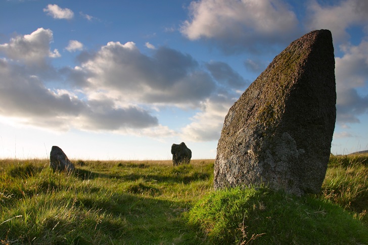 A large standing stone with moss around the base - part of a circle on green moorland