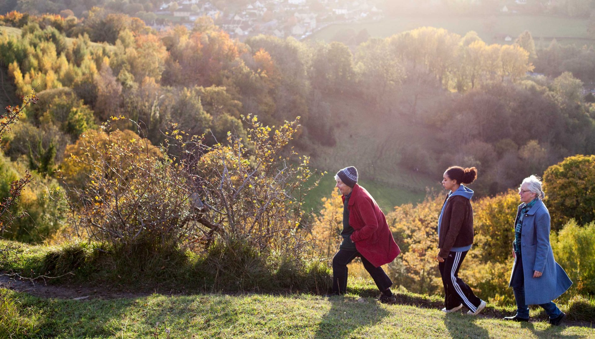 Autumnal colours across trees and fields and three generations of women on a walk