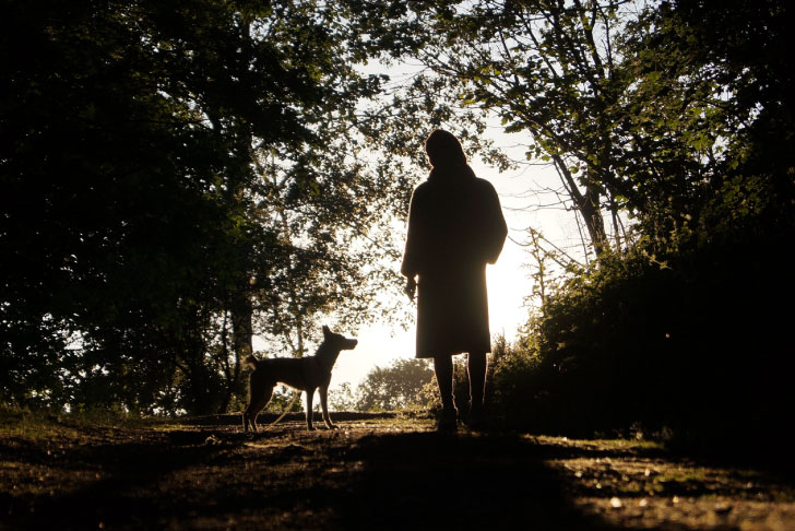 A woman in a warm coat and a small dog are silhouetted