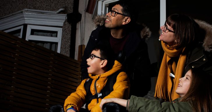 A family gathered in a garden looking to the night sky