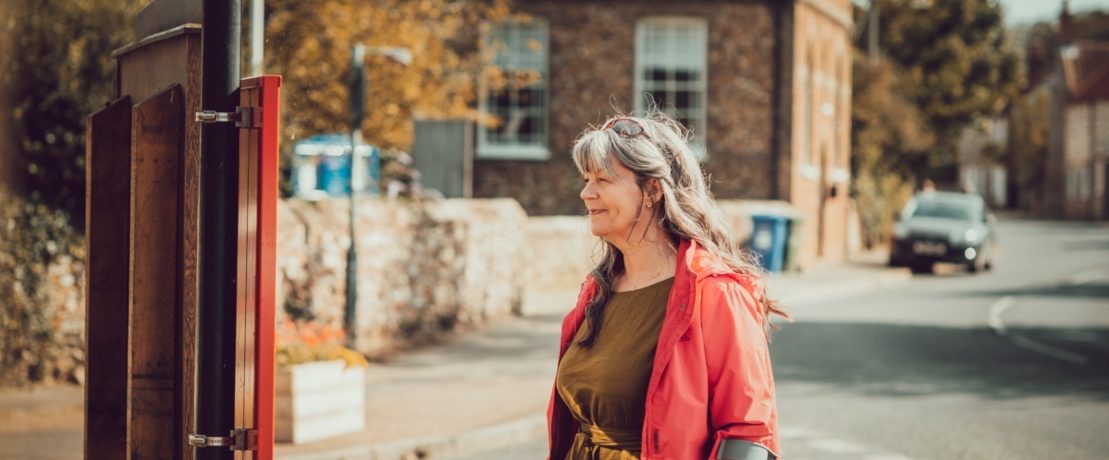 A woman waits at a village bus stop