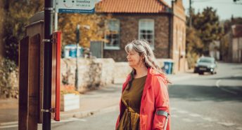 A woman waits at a village bus stop