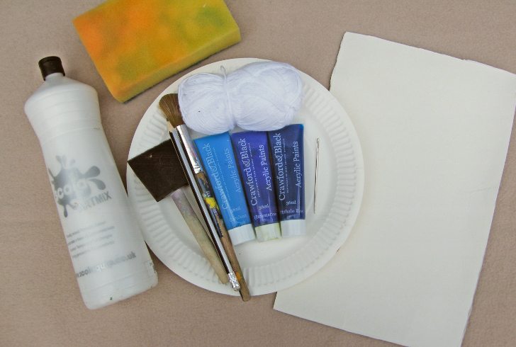 A paper plate with brushes, paint and cardboard