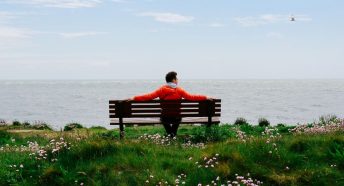 Man sitting by the coast on a bench