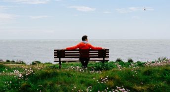 Man sitting by the coast on a bench