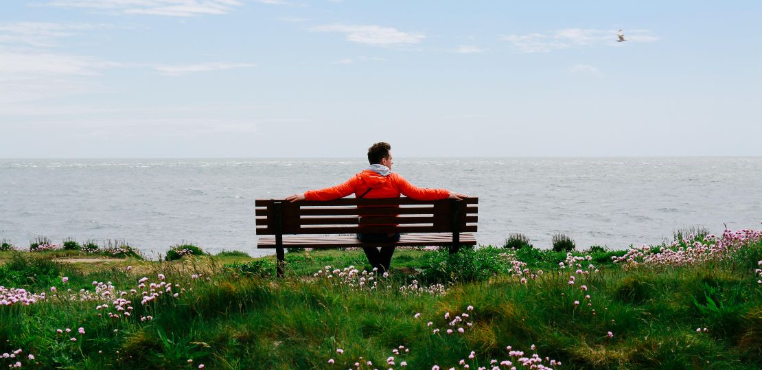 Man sitting by the coast on a bench