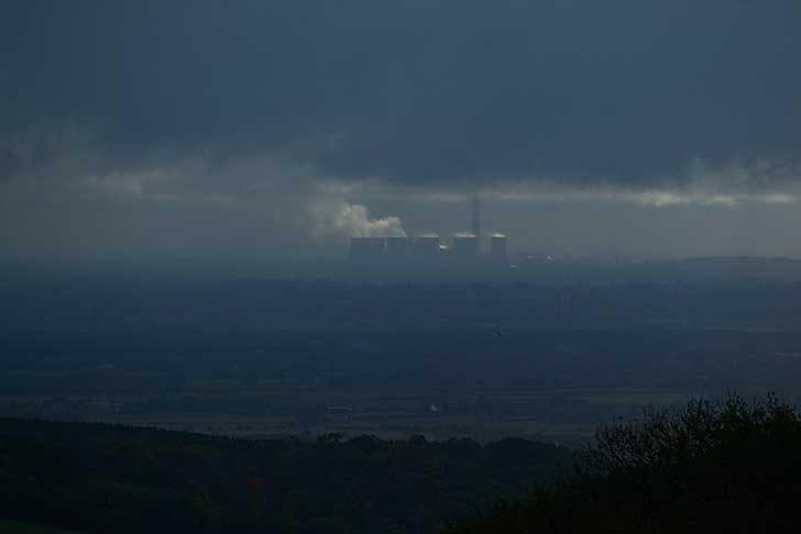 Aerial view of a power station from a distance, with smoke from the chimneys