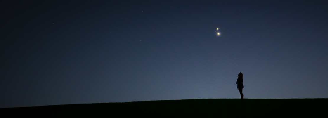 A woman looking up at bright objects in the night sky