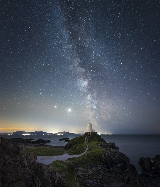 A star filled sky above a rocky coastline
