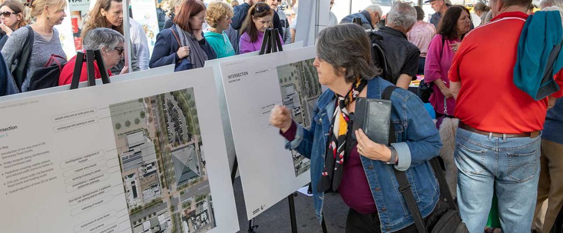 Crowds of people viewing outdoor boards showing new buildings