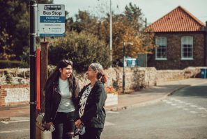 Mother and daughter wait at rural bus stop