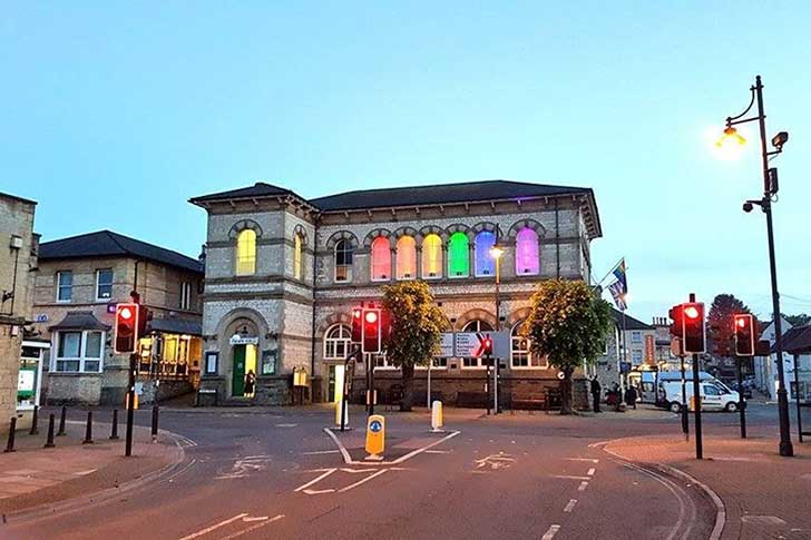 A stately municipal building with rainbow coloured lights shining in the windows
