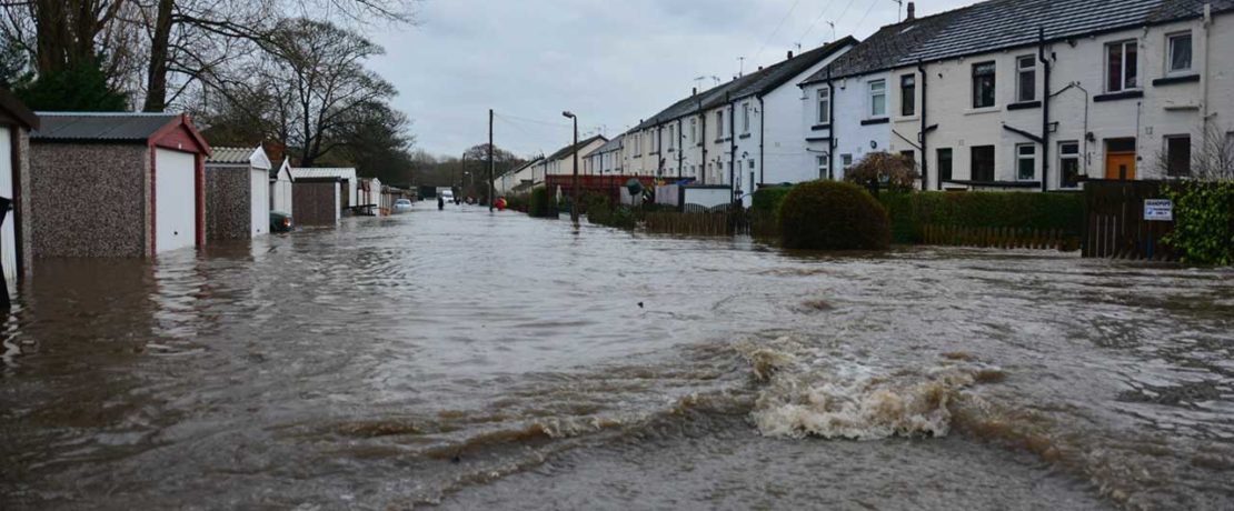 A flood of dirty brown water rushing along a terraced street