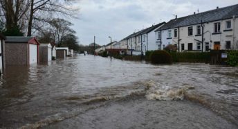 A flood of dirty brown water rushing along a terraced street