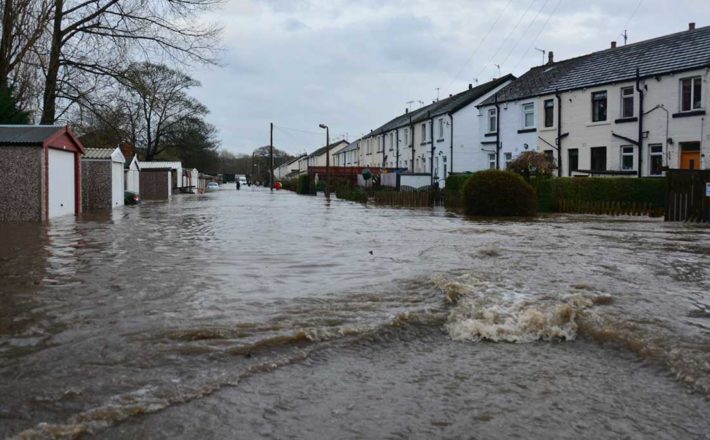 A flood of dirty brown water rushing along a terraced street