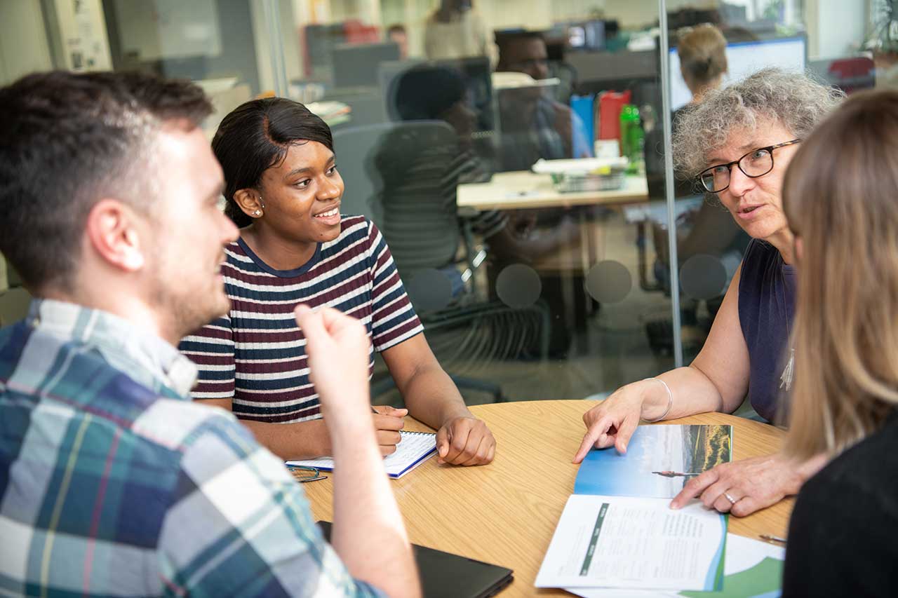 Several people around a table in an office chatting