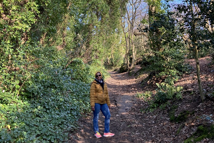 A woman walking up a steep footpath surrounded by trees