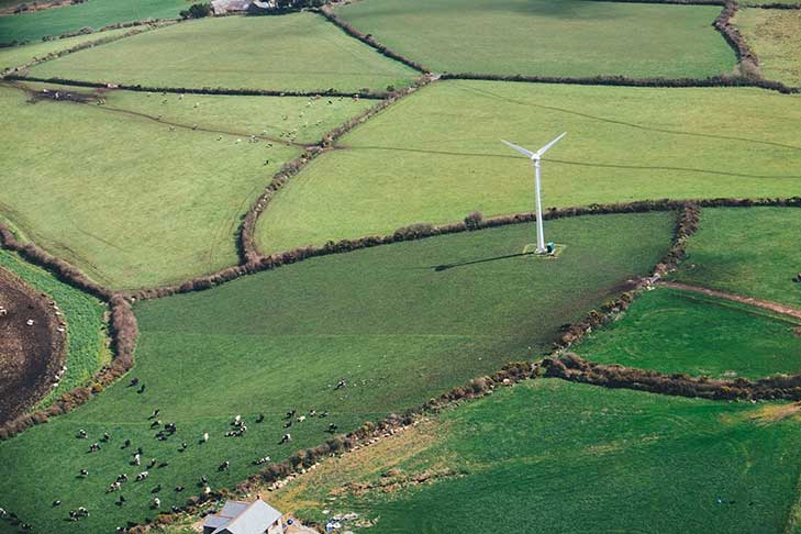 Aerial view of fields with hedgerows around and a wind turbine in a field