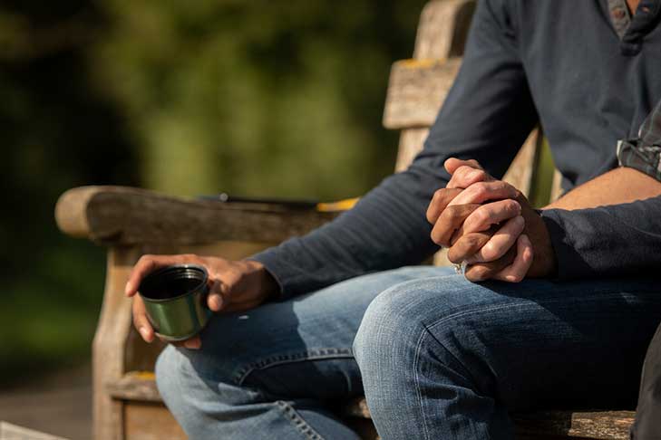 Detail of holding hands sitting on a sunny bench