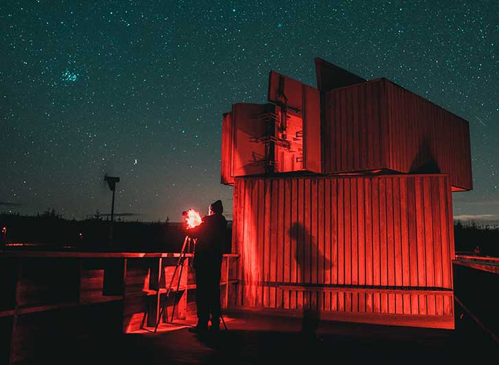 A low wooden building lit with deep red light against the night sky