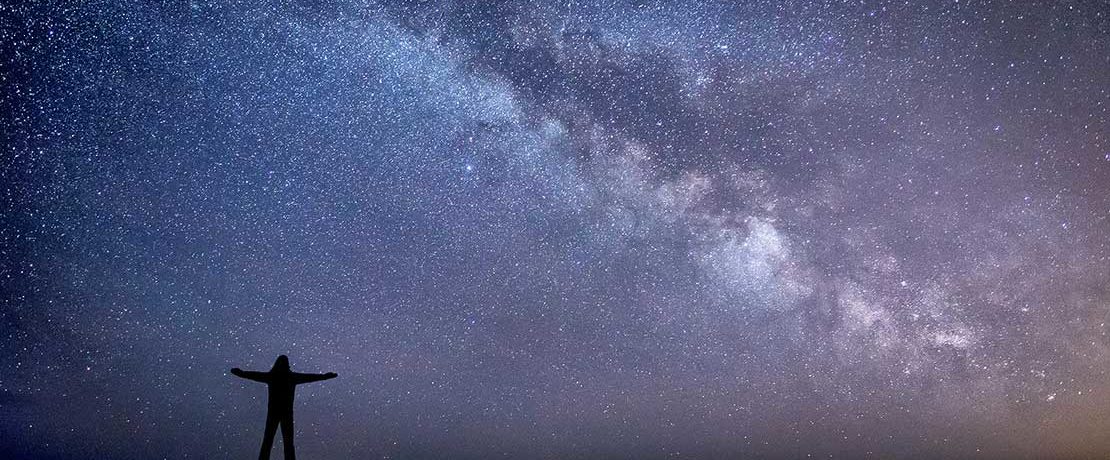 A figure silhouetted against a starry sky showing the Milky Way