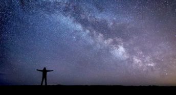 A figure silhouetted against a starry sky showing the Milky Way