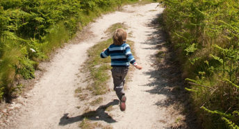boy running down sunny path in countryside