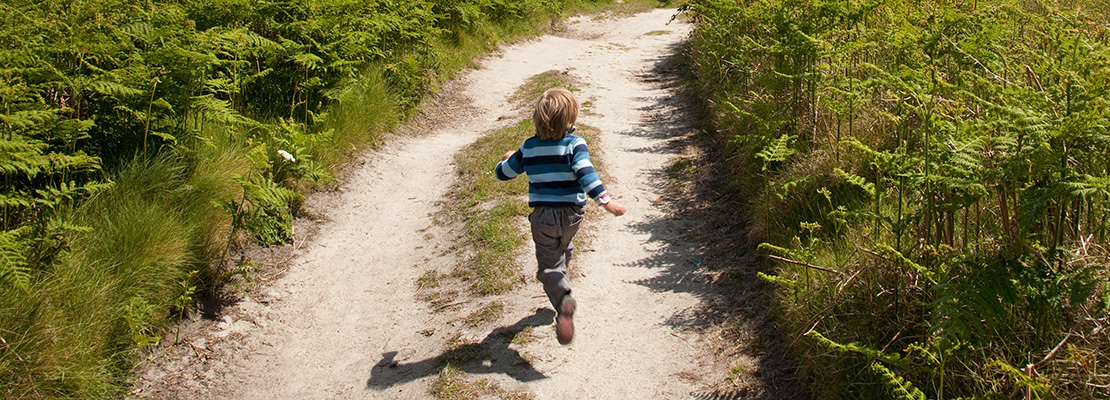 boy running down sunny path in countryside